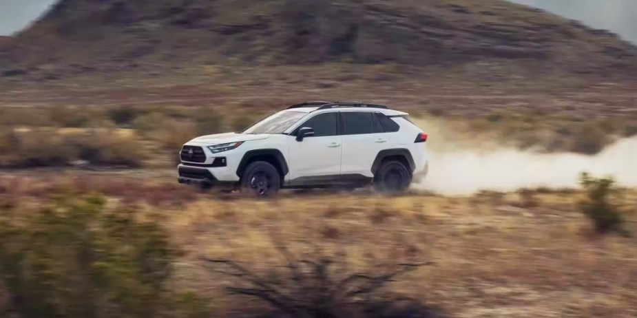 A white 2023 Toyota RAV4 small SUV is driving off-road. 