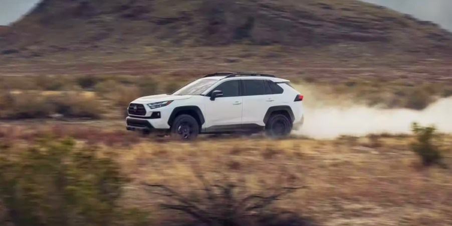 A white 2023 Toyota RAV4 small SUV is driving off-road.