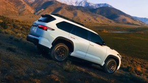 A white 2024 Toyota Sequoia full-size SUV is driving off-road.