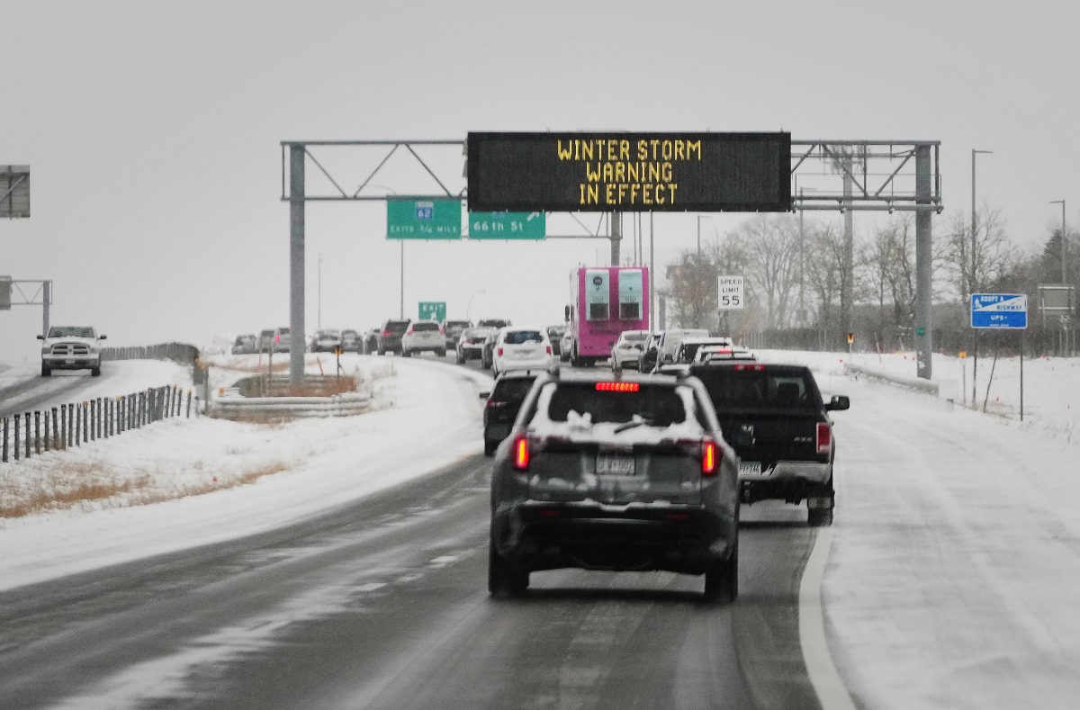 Cars drive along a wintery highway.