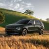 A 2024 Kia Niro compact hybrid SUV model parked in a dry wheat field framed by green grass hills