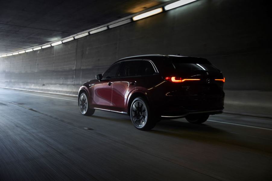 A rear shot of illuminated taillights on a 2024 Mazda CX-90 full-size SUV exiting into the light from a dark tunnel