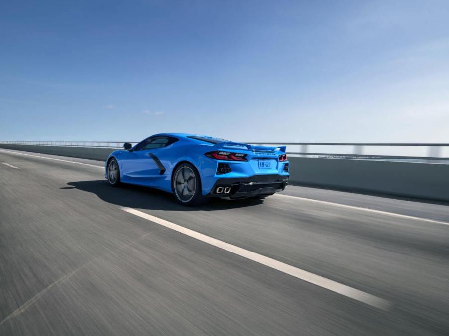 A 2024 Chevy Corvette Stingray performance sports car coupe model in Rapid Blue driving on a highway bridge