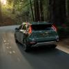 A 2023 Kia Niro compact hybrid SUV model driving on a forest road with its taillights lit up