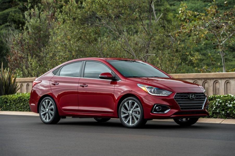 A 2022 Hyundai Accent subcompact sedan model parked next to bushes and a stone border