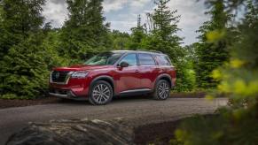 A 2024 Nissan Pathfinder midsize SUV model parked on a gravel trail within a forest