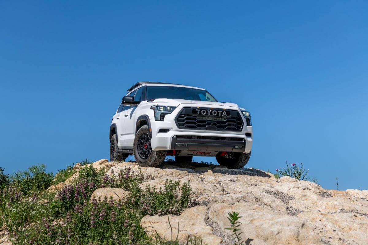 A 2024 Toyota Sequoia TRD-Pro midsize SUV model parked on a rocky hill covered in purple flowers