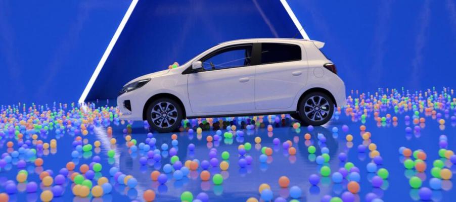 A side profile shot of a 2024 Mitsubishi Mirage subcompact hatchback model surrounded by multi-colored balls