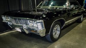 Dean Winchester's black 1967 Chevrolet Impala from 'Supernatural' sits at a car exhibit in a comic book showcase.