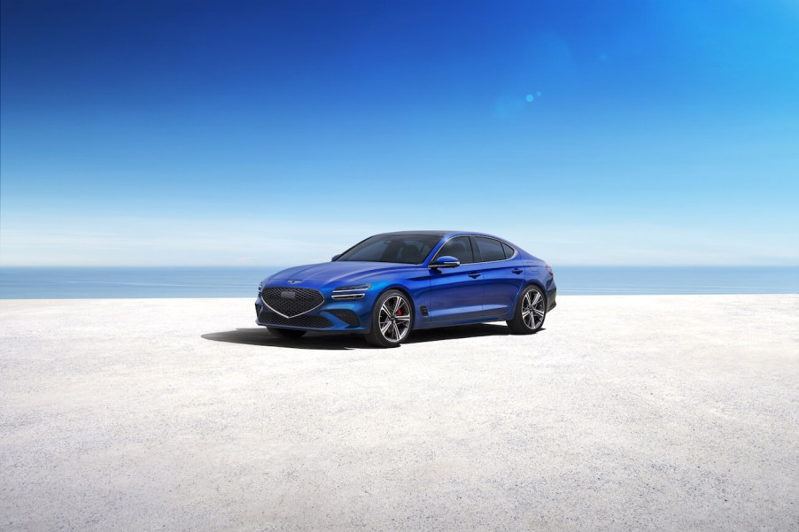 2023 Genesis G70 in blue parked on the shore. The G70 sales need to go up ASAP.