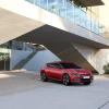 The top Kia EV – the 2023 Kia EV6 – pictured in red parked underneath a modern building.