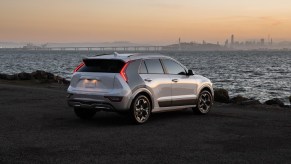 The 2023 Kia Niro EV parked on a cliff in front of water. The Kia Niro EV competes with the Hyundai Kona Electric.