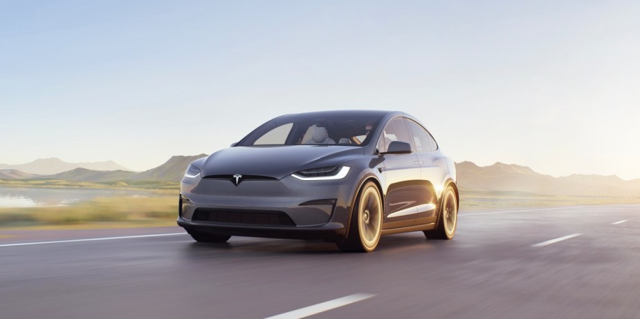 A gray 2023 Tesla Model X is driving on the road. 