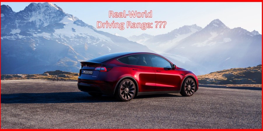 A red 2023 Tesla Model Y small electric SUV is parked facing the mountains.