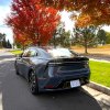 A rear view of the 2023 Toyota Prius Prime next to trees