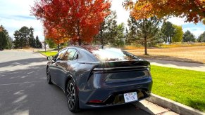 A rear view of the 2023 Toyota Prius Prime next to trees