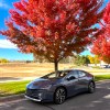 A front corner view of the 2023 Toyota Prius Prime next to trees