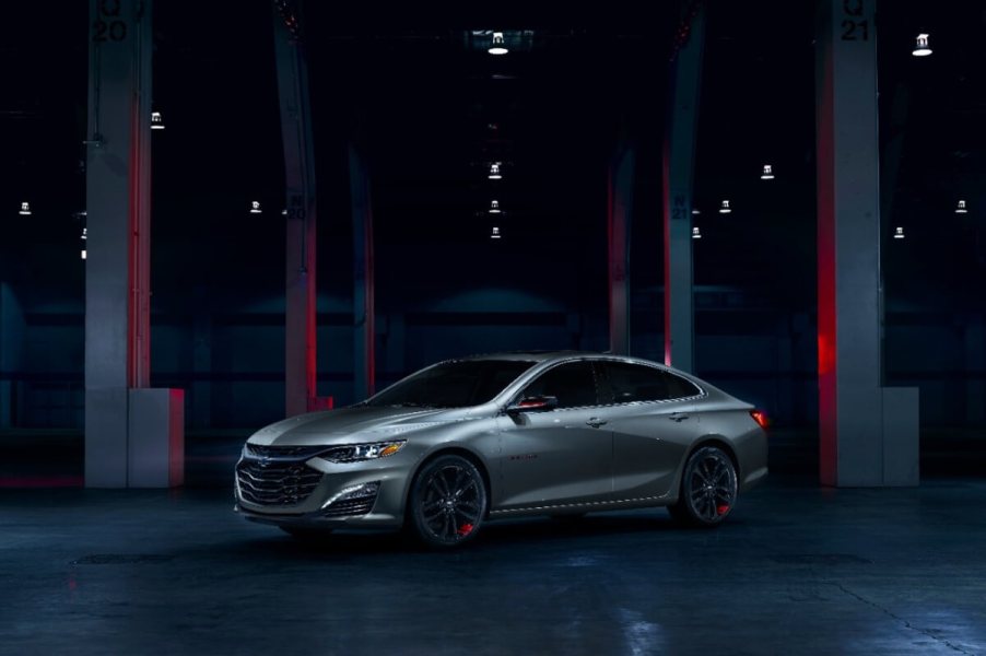 A gray 2024 Chevrolet Malibu, which shares styling with the 2023 model, sits in a dark garage.