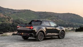 A black Hyundai Santa Cruz parked in front of some low mountains. It's behind Tacoma sales but just as good.