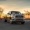 A 2024 Ram 3500 Limited Crew Cab heavy-duty pickup truck model parked by a stone ledge as the sun sets