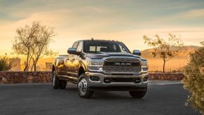 A 2024 Ram 3500 Limited Crew Cab heavy-duty pickup truck model parked by a stone ledge as the sun sets