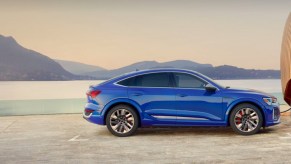 The side view of a blue Audi e-tron luxury midsize electric SUV.