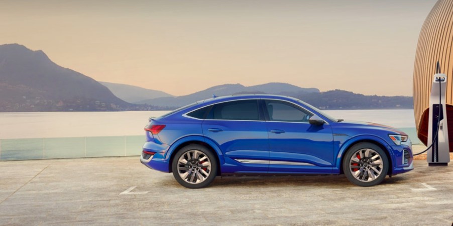 The side view of a blue Audi e-tron luxury midsize electric SUV.