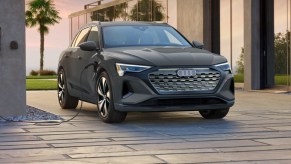 A gray Audi e-tron luxury electric midsize SUV is charging.