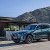 A blue BMW X5 driving down a hill with mountains behind. The X5 and 8 Series are holding back BMW sales this year.