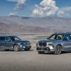 Two BMW X7 models parked in the desert in front of some mountains.