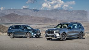 Two BMW X7 models parked in the desert in front of some mountains.