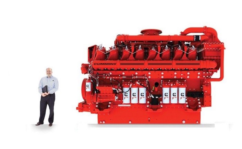 A man standing next to an 8-foot tall diesel locomotive engine.