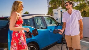 A man and woman plug their blue EV into a DC fast charger built and installed by EVgo.