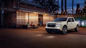 A silver Ford Maverick parked in a nicely decorated outdoor space at night. Ford hybrid sales are performing well this year.