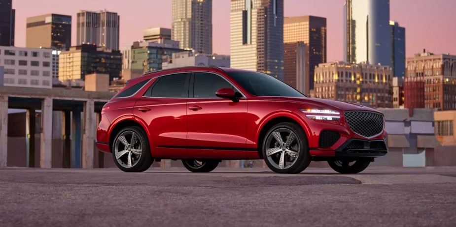 A red Genesis GV70 small luxury SUV is parked. 