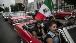 Lowrider passengers in Impala with 1962 Chevy behind