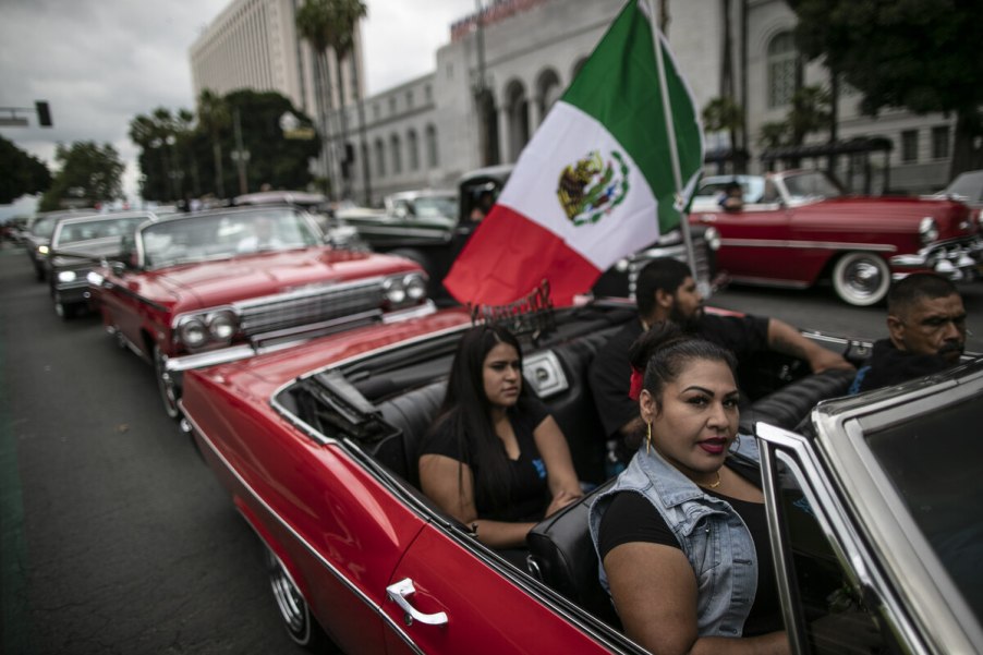 Lowrider passengers in Impala with 1962 Chevy behind