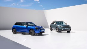 Two blue Mini Cooper models parked against a white backdrop and blue sky. This is the most dependable sports car in 2023.