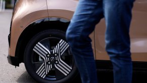 Closeup of the wheel and tire of a Nissan Sakura KEI-class EV, a person walking by in the foreground.