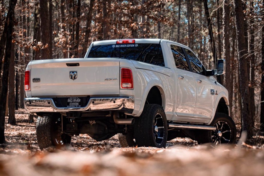 A white heavy-duty Ram truck with a Cummins engine parked in the woods.