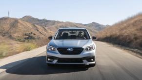 A Subaru Legacy driving down an open road.