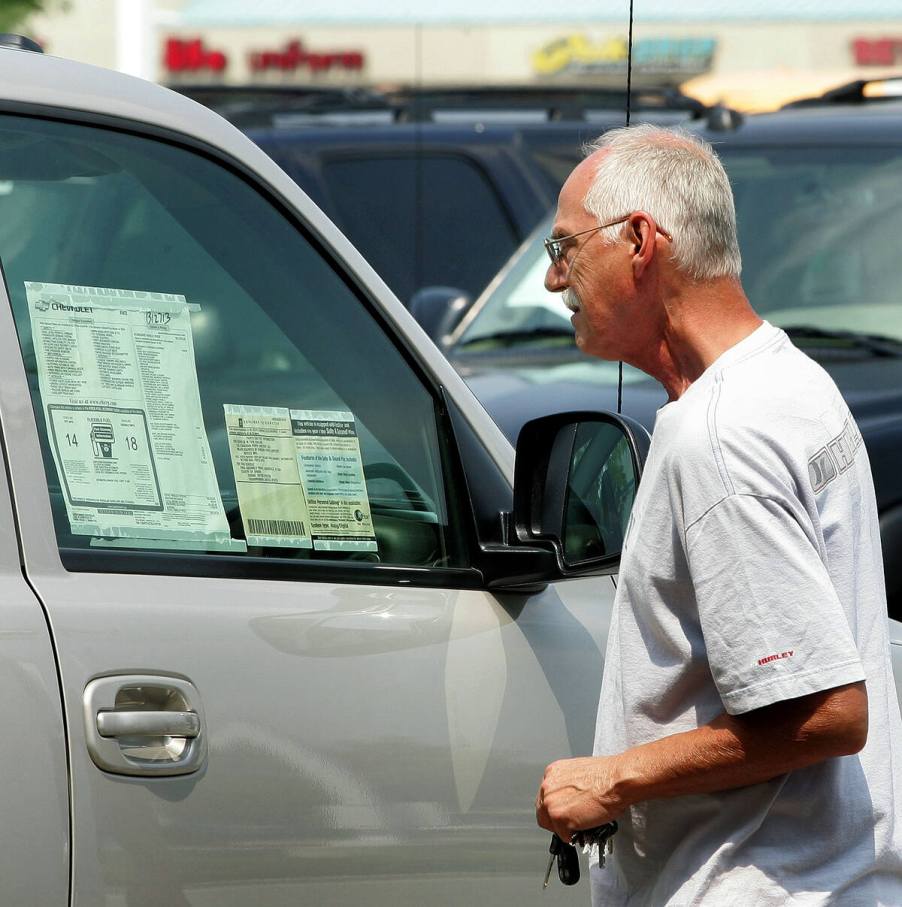 Man looking at vehicle window sticker