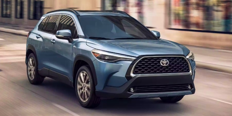 A blue Toyota Corolla Cross subcompact SUV is driving on the road.