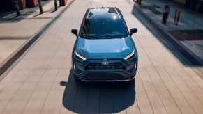 A blue 2024 Toyota RAV4 Hybrid small hybrid SUV is driving.