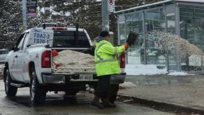 A worker pours road salt onto the street during winter.