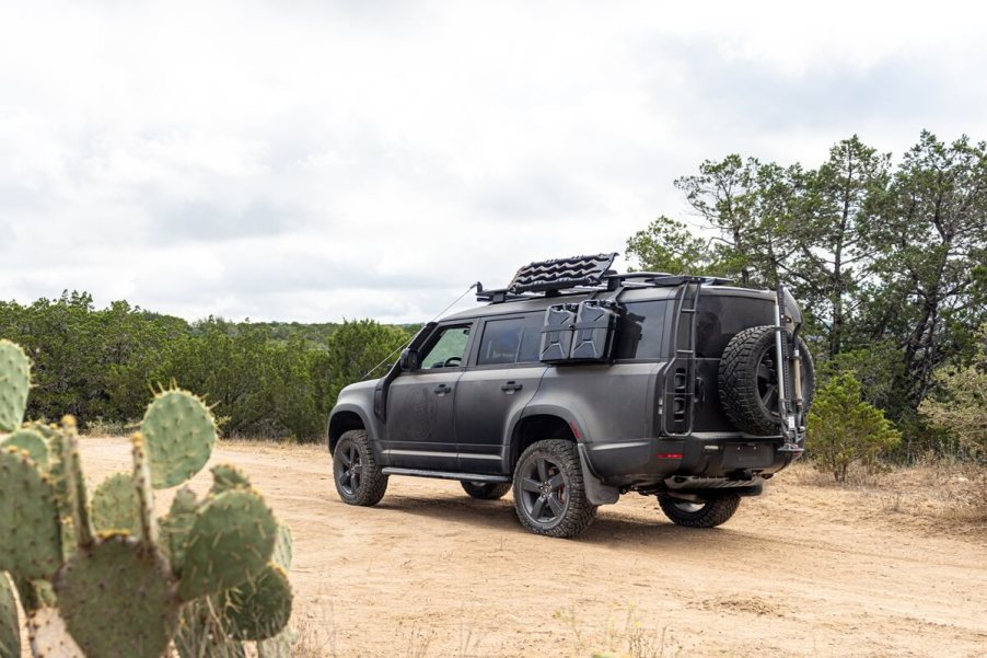 A matte black 2024 Land Rover Defender 130 sits on a trail at TReK in Texas.