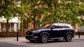 A 2024 Infiniti QX60 midsize luxury crossover XUV model parked in a plaza near trees and bollards