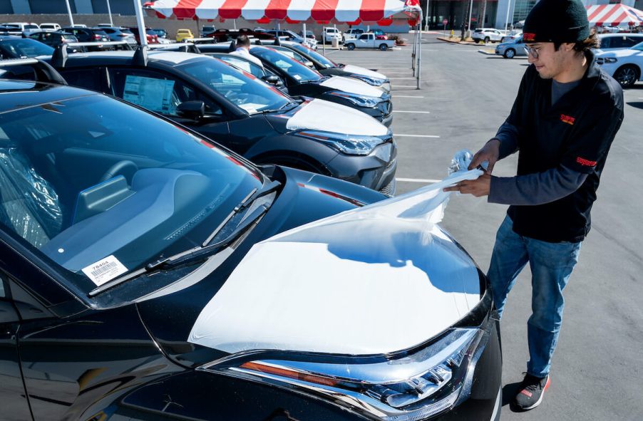 A car lot detailer pulls the wraps off a new car