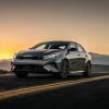 A 2024 Kia Forte GT compact sedan model parked on an asphalt country highway as the sun sets