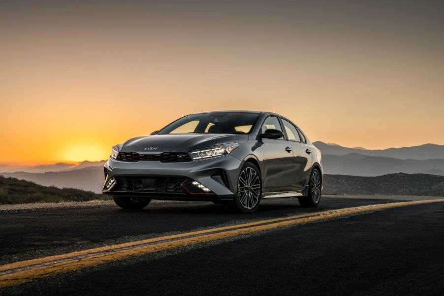 A 2024 Kia Forte GT compact sedan model parked on an asphalt country highway as the sun sets